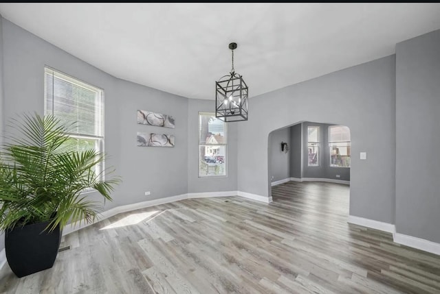 unfurnished dining area with hardwood / wood-style floors and a notable chandelier