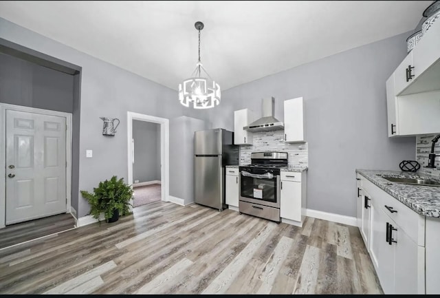 kitchen featuring white cabinets, appliances with stainless steel finishes, sink, and wall chimney range hood