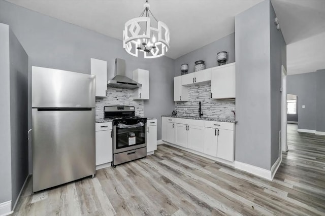 kitchen with appliances with stainless steel finishes, decorative light fixtures, white cabinetry, decorative backsplash, and wall chimney range hood