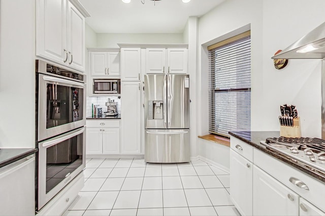 kitchen featuring white cabinets, extractor fan, light tile patterned floors, and appliances with stainless steel finishes