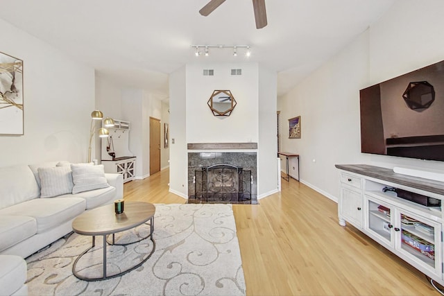 living room featuring light hardwood / wood-style floors, ceiling fan, and a high end fireplace