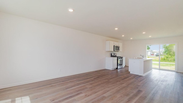 kitchen featuring light hardwood / wood-style floors, white cabinets, appliances with stainless steel finishes, and a kitchen island with sink