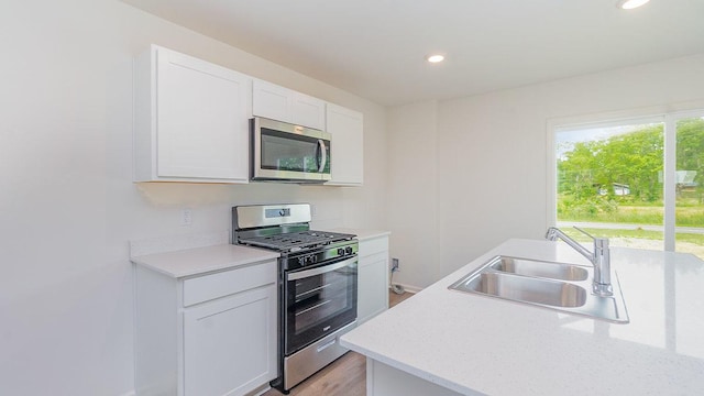 kitchen with sink, white cabinetry, light hardwood / wood-style flooring, and appliances with stainless steel finishes