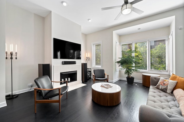 living room with dark wood-type flooring, ceiling fan, and a tile fireplace