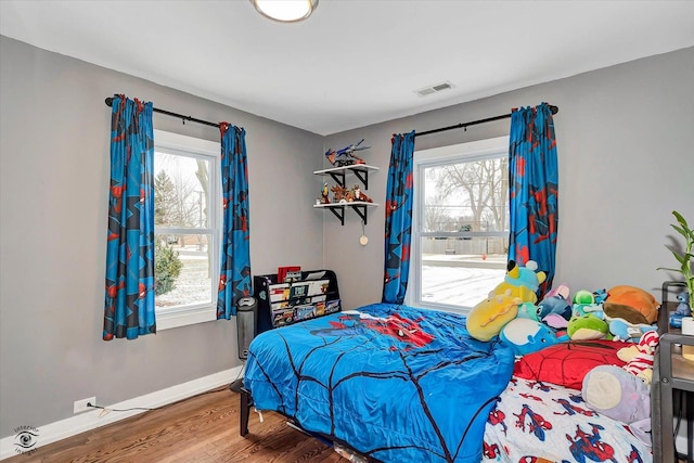 bedroom with multiple windows and hardwood / wood-style flooring