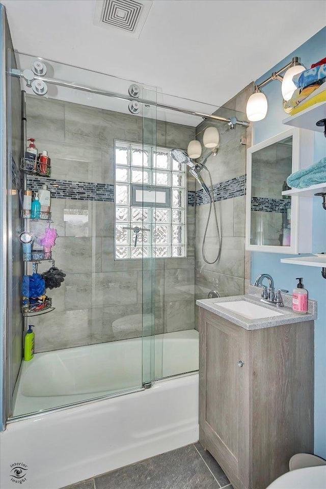 bathroom featuring tile patterned flooring, enclosed tub / shower combo, and vanity