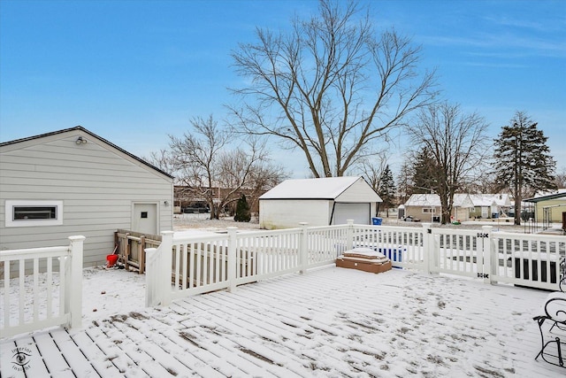 snow covered deck with an outbuilding and a garage