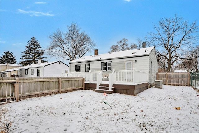 snow covered house featuring cooling unit and a wooden deck