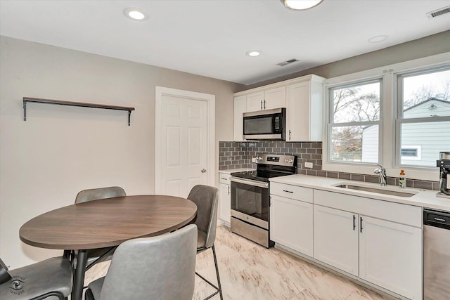 kitchen featuring white cabinetry, sink, decorative backsplash, and appliances with stainless steel finishes