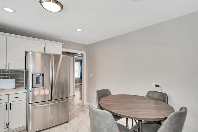 kitchen featuring white cabinetry, decorative backsplash, and stainless steel refrigerator with ice dispenser