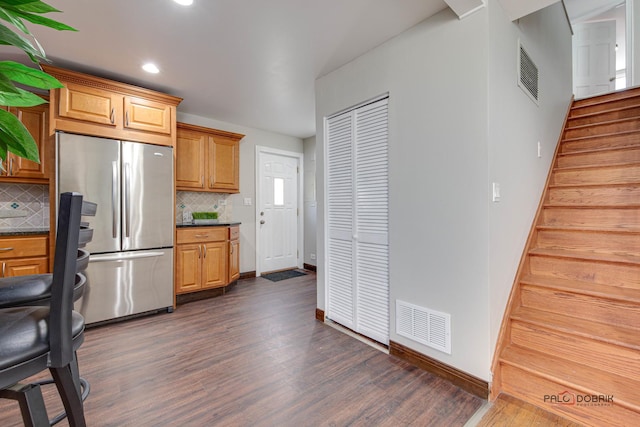 kitchen with backsplash, stainless steel fridge, and dark hardwood / wood-style floors