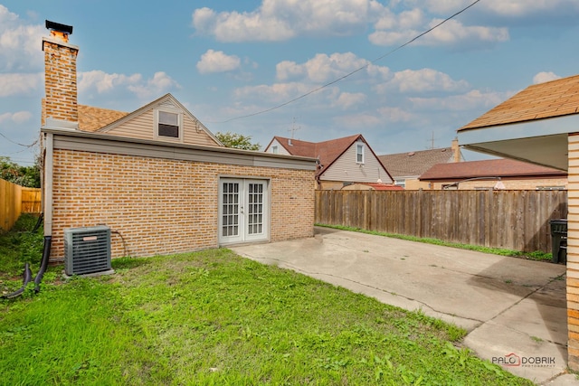 back of property with a patio, french doors, central AC unit, and a yard