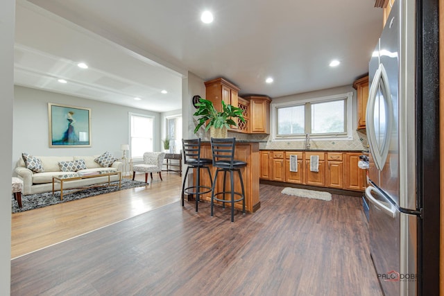 kitchen featuring a breakfast bar, backsplash, stainless steel fridge, and dark hardwood / wood-style floors