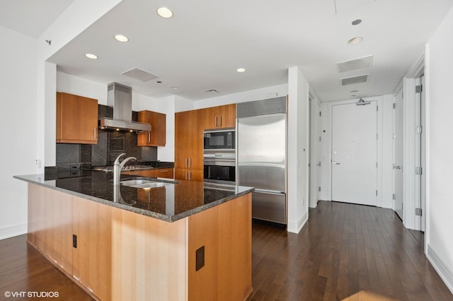 kitchen with extractor fan, built in appliances, tasteful backsplash, dark stone countertops, and kitchen peninsula