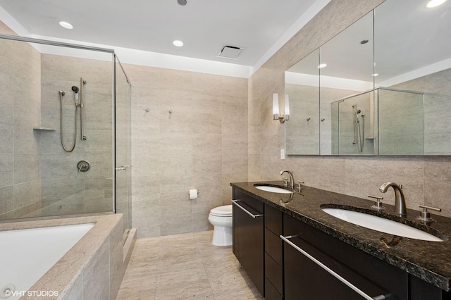 full bathroom with independent shower and bath, toilet, vanity, and tile walls