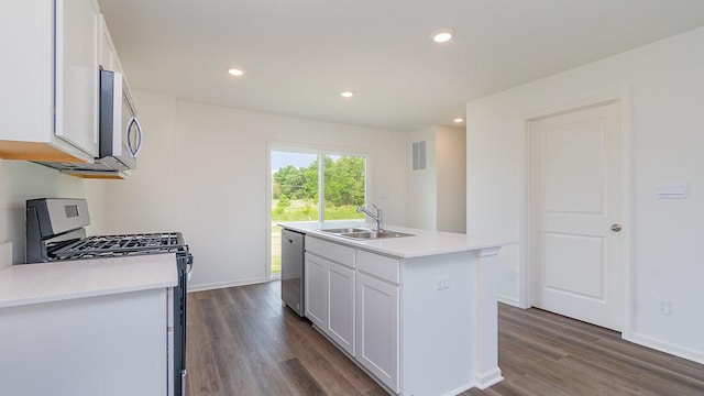 kitchen with white cabinets, appliances with stainless steel finishes, an island with sink, sink, and dark hardwood / wood-style floors