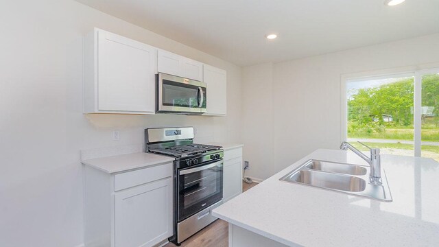 kitchen featuring sink, white cabinets, light hardwood / wood-style flooring, and appliances with stainless steel finishes