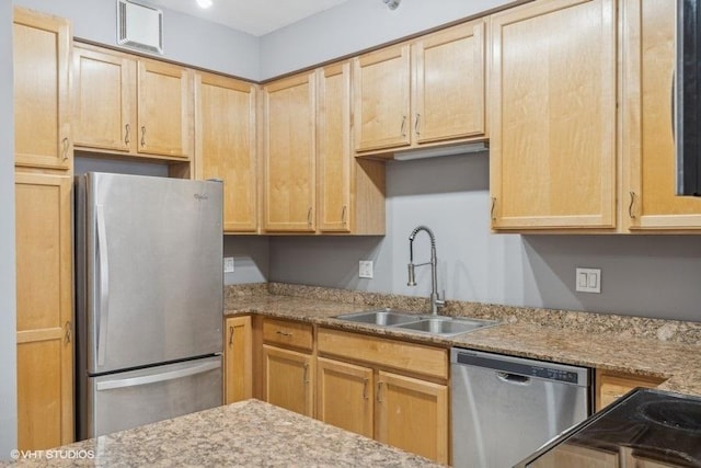 kitchen featuring light stone countertops, sink, light brown cabinets, and appliances with stainless steel finishes