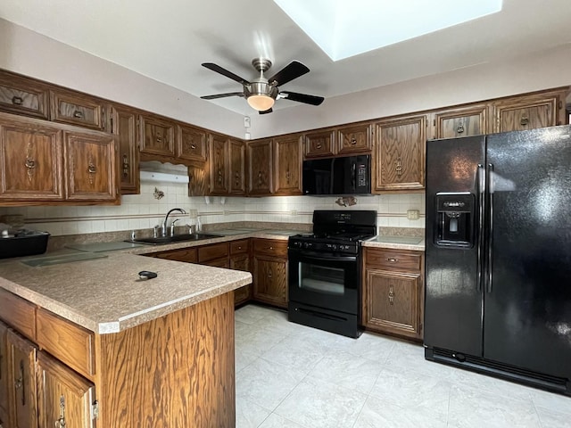 kitchen with kitchen peninsula, sink, decorative backsplash, and black appliances