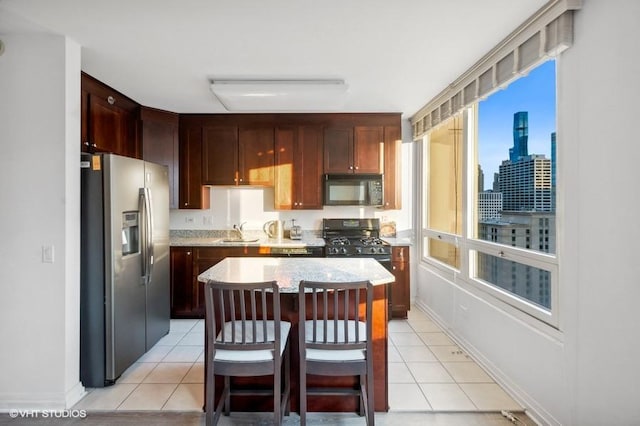 kitchen with black appliances, a center island, sink, a breakfast bar, and light tile patterned flooring