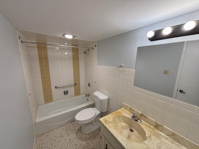 full bathroom with toilet, tile walls, tile patterned floors, vanity, and tiled shower / bath