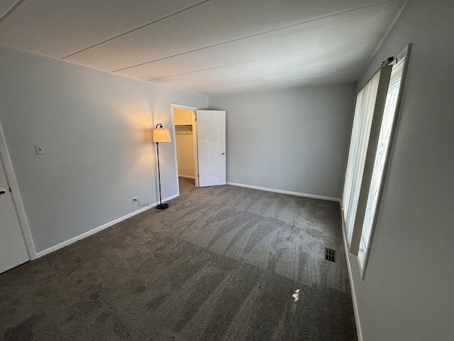 unfurnished bedroom with a walk in closet, carpet floors, and multiple windows