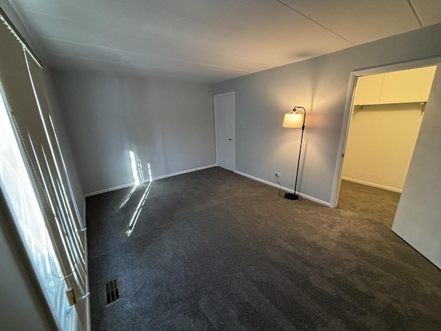 unfurnished bedroom featuring dark colored carpet and a closet