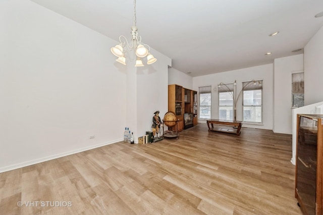 unfurnished dining area with a notable chandelier, baseboards, and wood finished floors