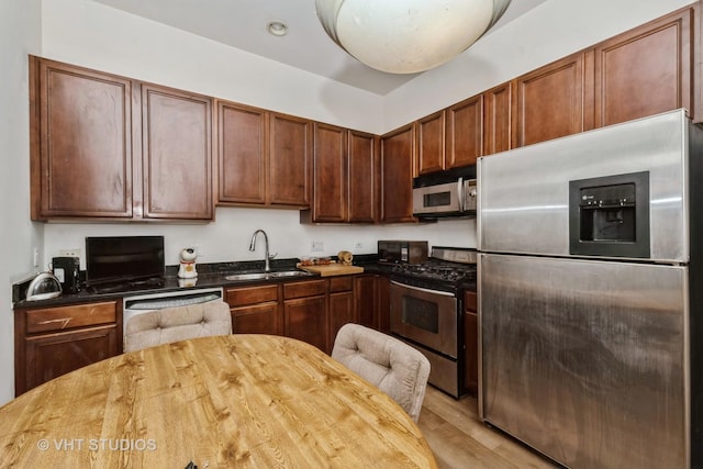 kitchen with stainless steel appliances, recessed lighting, light wood-style floors, a sink, and wood counters