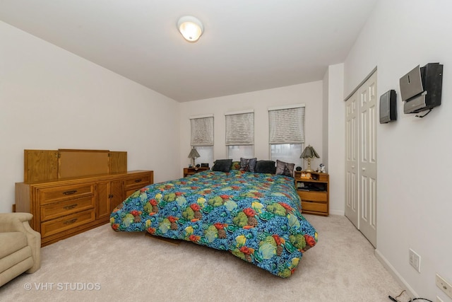 bedroom with baseboards, a closet, and light colored carpet