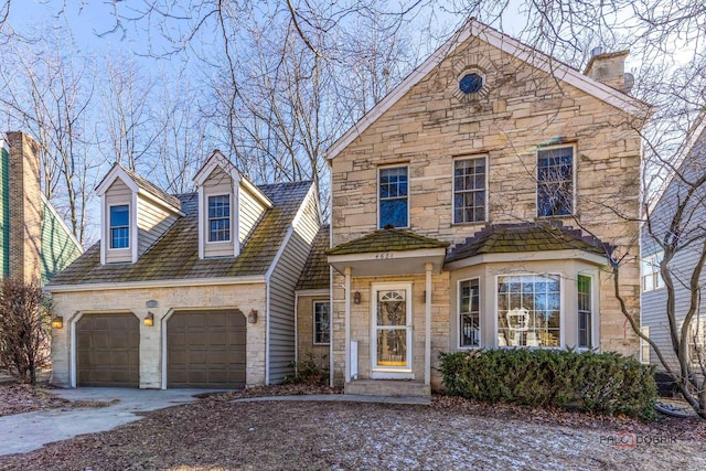 view of front of home with a garage, stone siding, and driveway