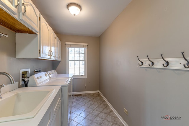 clothes washing area featuring a sink, baseboards, cabinet space, and washer and clothes dryer