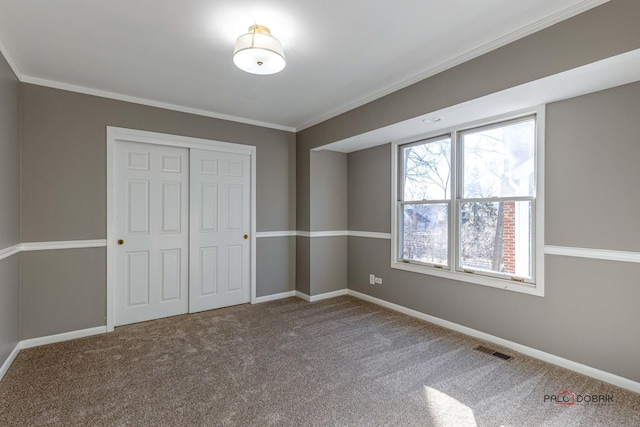 unfurnished bedroom featuring a closet, visible vents, carpet, and ornamental molding