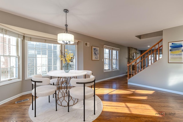 dining area with visible vents, a healthy amount of sunlight, wood finished floors, and stairs