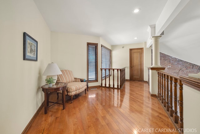 living area featuring decorative columns and hardwood / wood-style floors