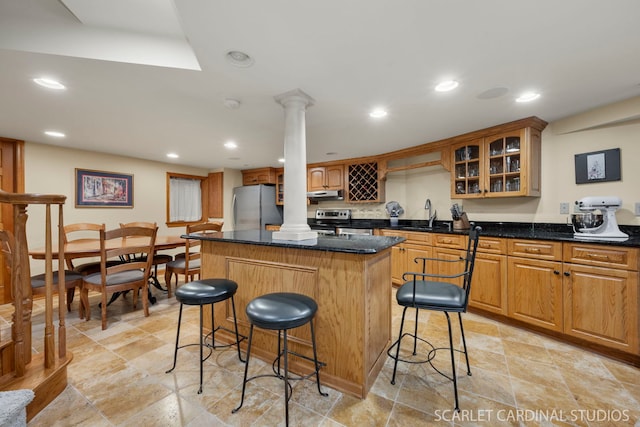 kitchen with sink, a breakfast bar, stainless steel appliances, a center island, and decorative columns