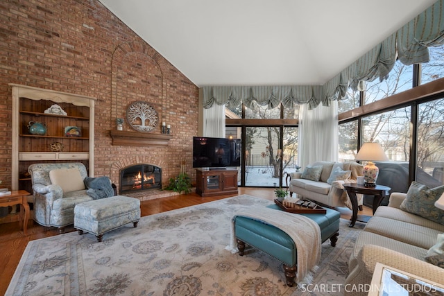 living room with a brick fireplace, built in shelves, wood-type flooring, and high vaulted ceiling