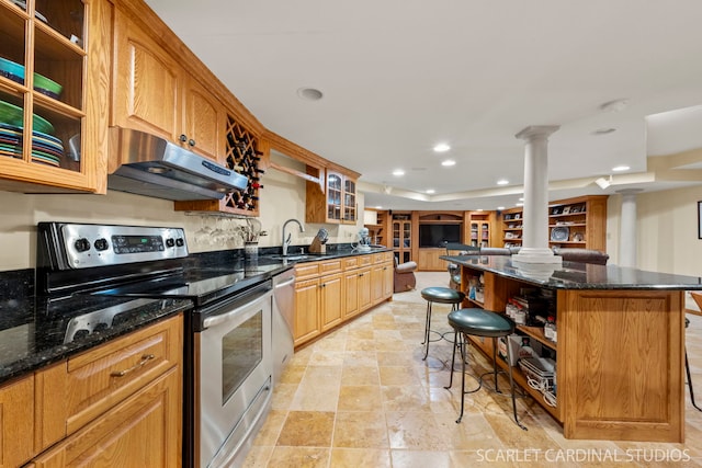 kitchen featuring sink, ornate columns, a center island, appliances with stainless steel finishes, and a kitchen breakfast bar