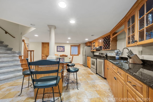 kitchen featuring dark stone countertops, sink, ornate columns, and appliances with stainless steel finishes