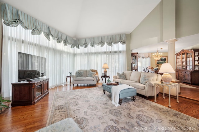 living room with ornate columns, high vaulted ceiling, hardwood / wood-style floors, and a chandelier