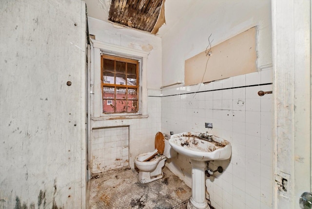 bathroom featuring toilet and tile walls