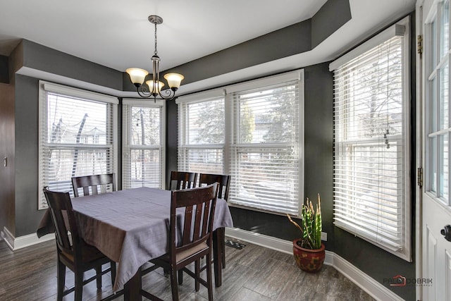 dining area with dark wood-type flooring and an inviting chandelier