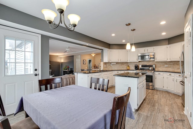 dining space with sink, ceiling fan with notable chandelier, and light hardwood / wood-style floors