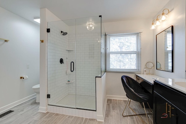 bathroom featuring vanity, a shower with shower door, and toilet