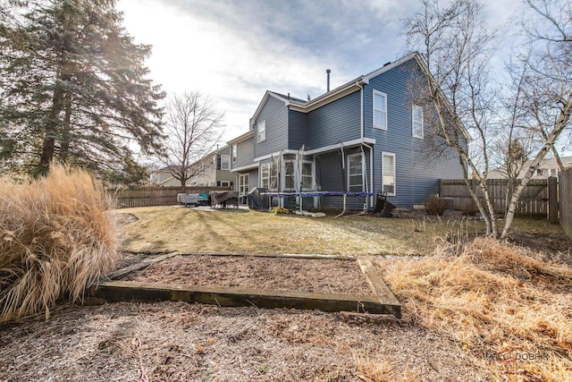 rear view of house with a yard and a trampoline