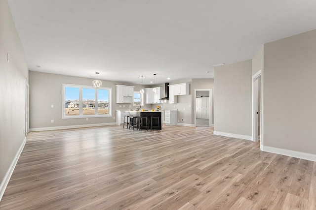 unfurnished living room featuring sink and light wood-type flooring