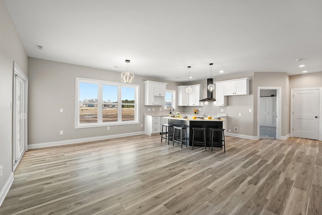 kitchen with white cabinets, a kitchen island, a breakfast bar area, and wall chimney exhaust hood