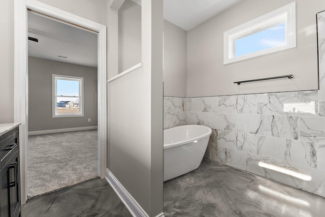 bathroom featuring vanity, a washtub, and tile walls