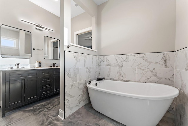 bathroom featuring concrete floors, a bath, vanity, and tile walls