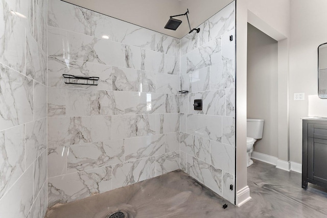 bathroom with a tile shower, toilet, and vanity